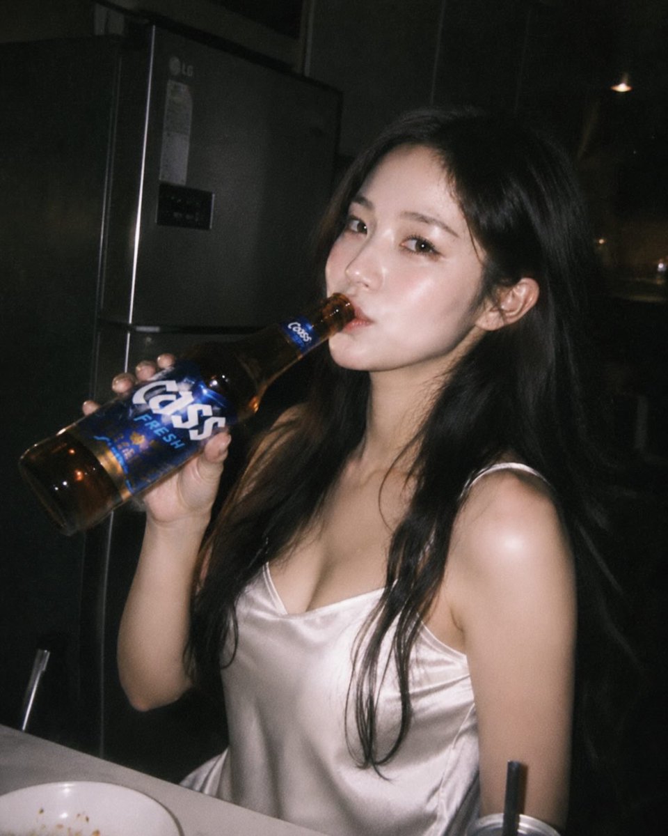 AI-generated ultra-realistic candid kitchen night woman portrait featuring an East Asian woman holding a beer bottle, illuminated by refrigerator light in a dimly lit kitchen.