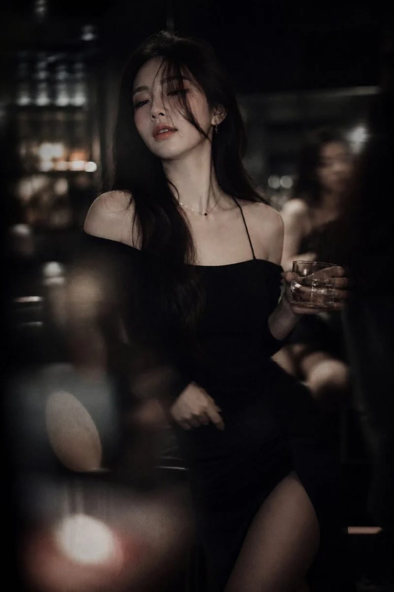 A striking AI-generated low light Korean idol nightlife portrait, featuring a female idol in a dimly lit bar, exuding a mysterious and alluring aura.