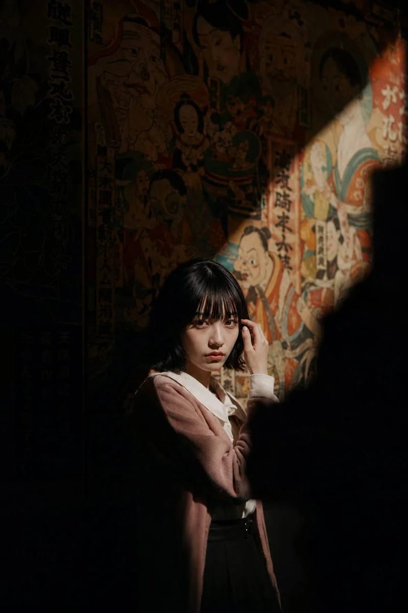 Cinematic portrait of a woman illuminated by a dramatic spotlight against a colorful vintage Japanese mural, embodying a museum spotlight Japanese mural portrait aesthetic.